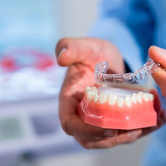 Webster orthodontist placing Invisalign on model of teeth