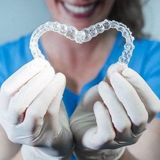 dentist holding two Invisalign aligners in heart shape 
