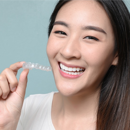 Smiling woman holding Invisalign tray