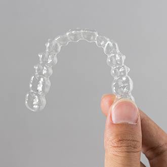 hand holding Invisalign clear aligner