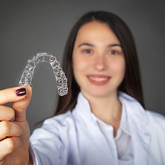 Woman holding up an Invisalign tray