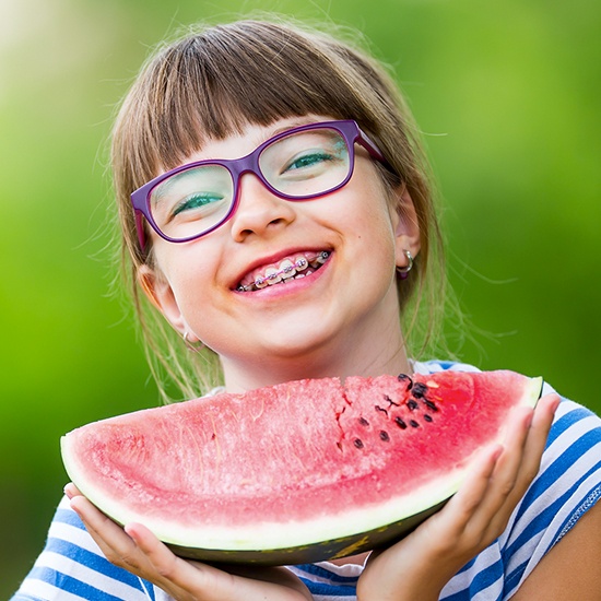 Young girl receiving pediatric orthodontics eating watermelon
