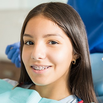 Teen girl with braces in orthodontic chair smiling