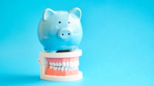 Piggy bank atop model teeth straightened by braces in Webster