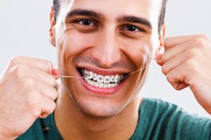 Smiling man flossing with braces