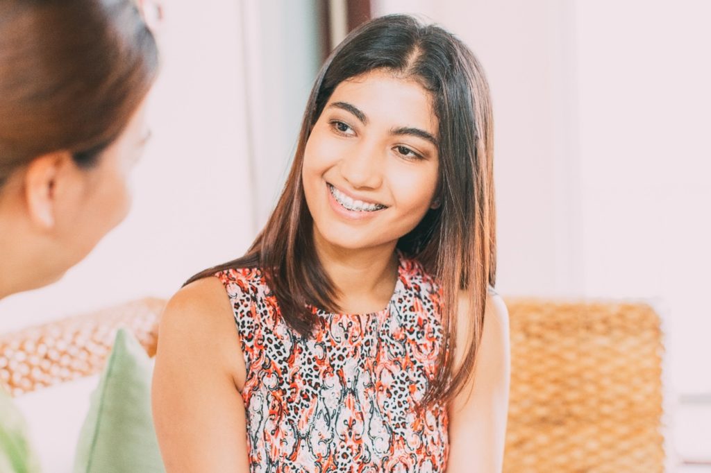 Closeup of woman with braces smiling at friend