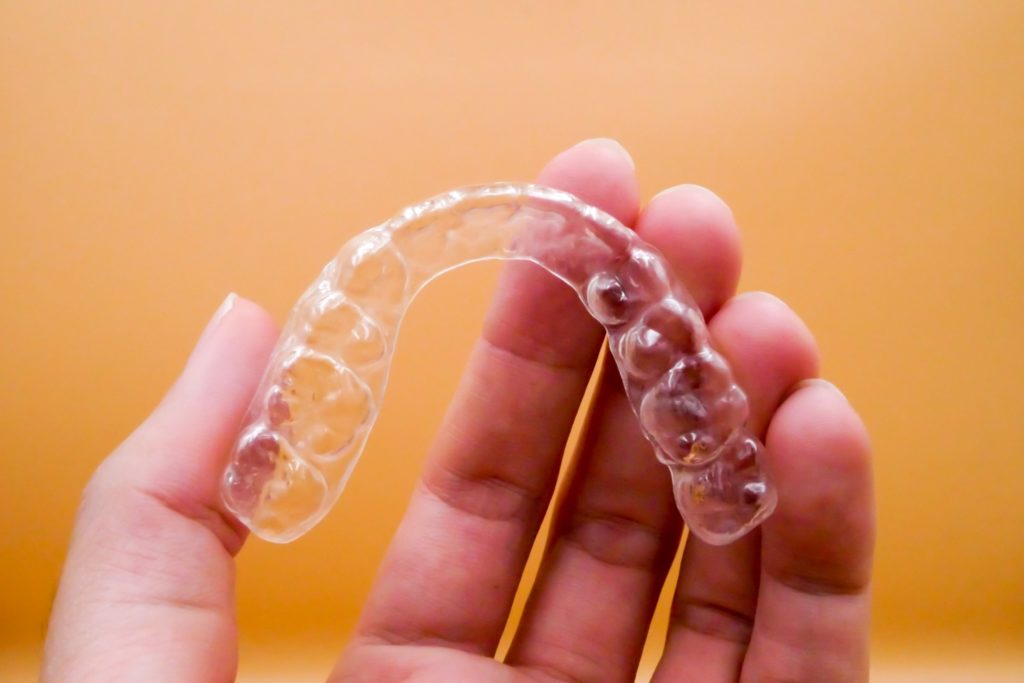 Patient holding up Invisalign retainer