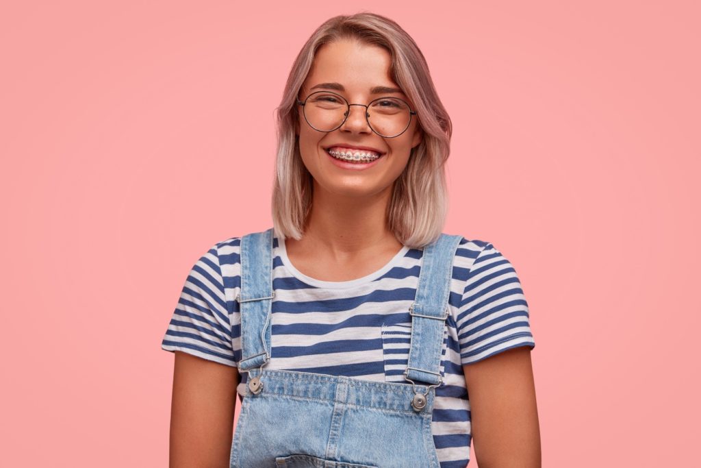 Woman with braces and overalls smiling