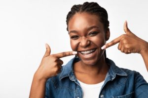 Smiling girl pointing to her braces in Webster