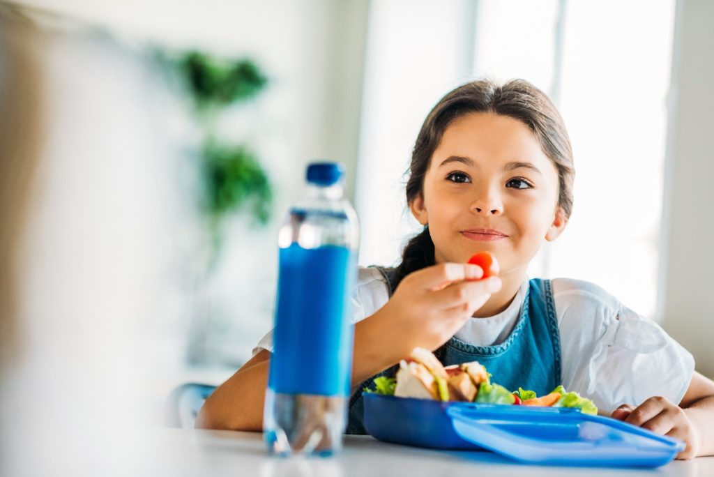 Child smiling while eating lunch at school